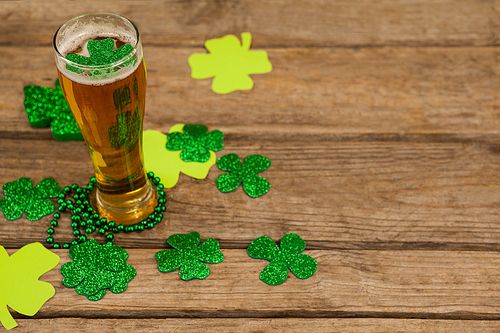 Glass of beer, beads and shamrock for St Patricks Day on wooden table