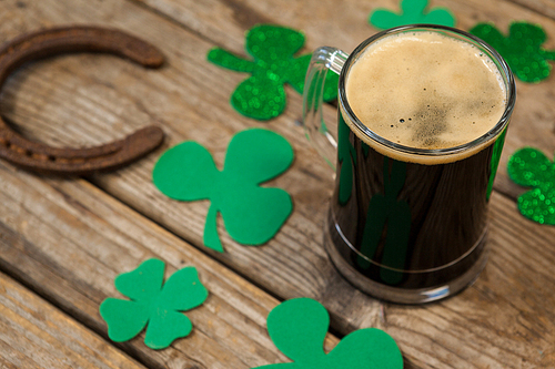 Glass of black beer, horseshoe and shamrock for St Patricks Day on wooden table