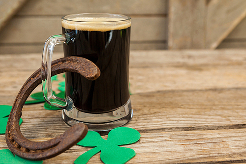 Glass of black beer, horseshoe and shamrock for St Patricks Day on wooden table