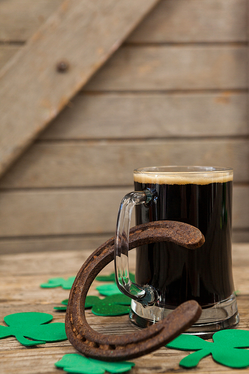 Glass of black beer, horseshoe and shamrock for St Patricks Day on wooden table