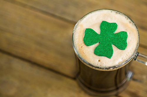 St Patricks Day mug of beer with shamrock on wooden surface
