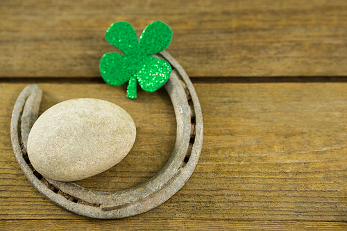 St Patricks Day shamrocks with horseshoe and pebble on wooden surface