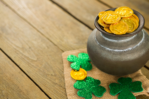 St. Patricks Day shamrock and pot filled with chocolate gold coins on wooden table
