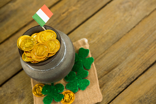 St. Patricks Day shamrock, flag and pot filled with chocolate gold coins on wooden table