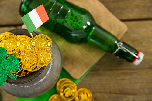St. Patricks Day shamrock, flag, beer bottle and pot filled with chocolate gold coins on wooden table