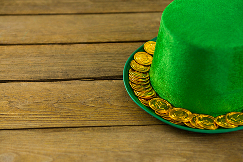 St Patricks Day leprechaun hat with gold chocolate gold coins on wooden background