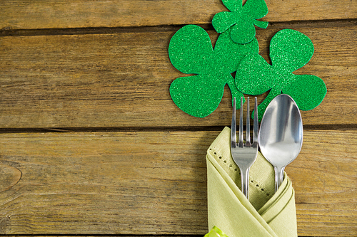 St Patricks Day fork and spoon wrapped in napkin with shamrocks on wooden table