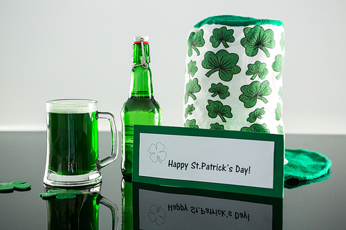 Green beer with shamrock, leprechaun hat and placard of St Patricks Day on table