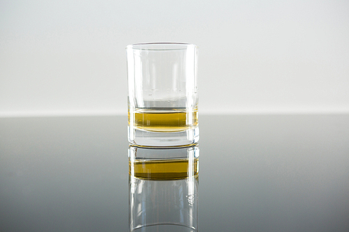 Glass of whisky on table against white background