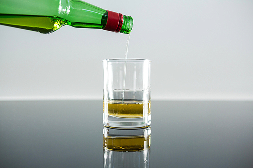 Whiskey being poured into a glass against white background