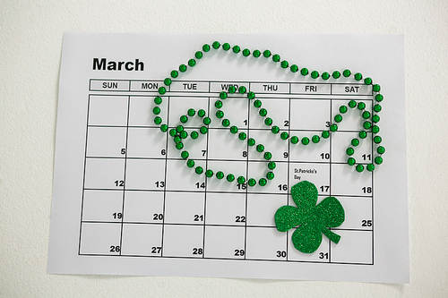 St. Patricks Day shamrock and beads kept on calendar on white background