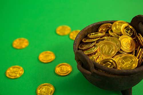 St. Patricks Day pot filled with chocolate gold coins on green background