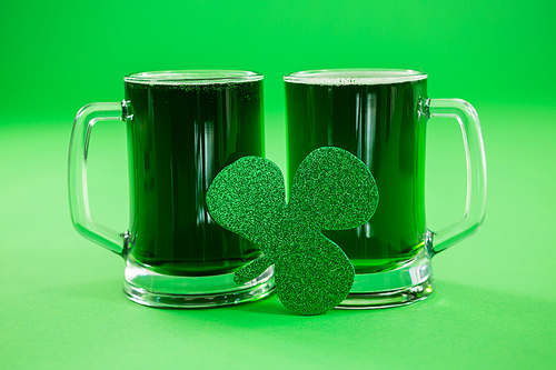 St Patricks Day two mugs of green beer with shamrock on green background