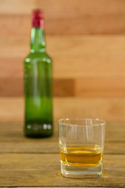 Whiskey bottle and glass kept on wooden table