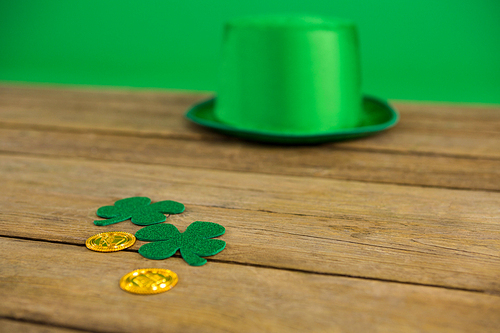 St Patricks Day leprechaun hat with shamrock and gold chocolate coin on wooden background