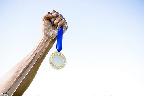 Cropped image of athlete holding gold medal against clear sky