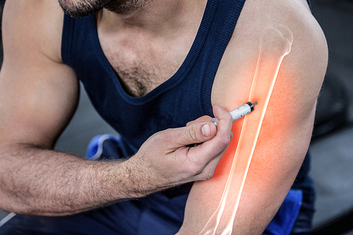 Digital composite of highlighted arm of strong man injecting anabolic steroid at gym