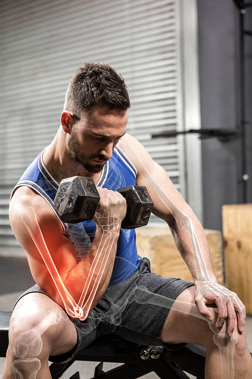 Determinated male athlete doing excercise with dumbbells at gym