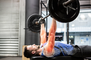 Male athlete exercising with barbell at gym