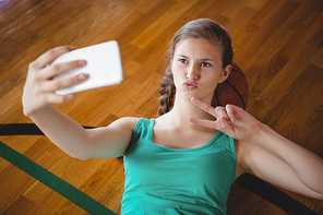 Overhead view of female basketball player gesturing while taking selfie in court