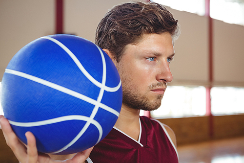 Close up of serious basketball player holding ball while standing in court