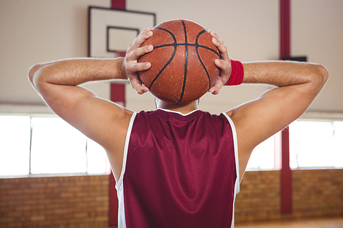 Rear view of basketball player holding ball while practicing in court