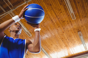 Low angle view of male teenager with basketball in court