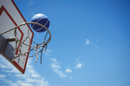 Low angle view ofblue basketball in hoop against blue sky