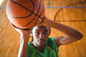 High angle view of teenage boy practicing basketball in court