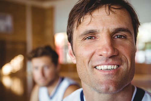 Close up portrait of smiling basketball player with friend in background