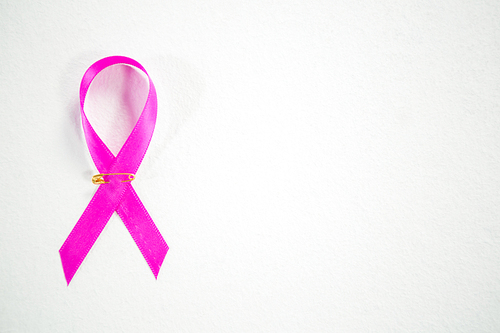 Overhead view of pink Breast Cancer Awareness ribbon on white background