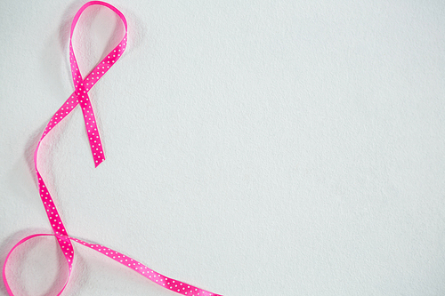 Overhead view of pink spotted Breast Cancer Awareness ribbon on white background