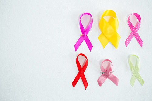 Directly above view of various awareness ribbons on white background