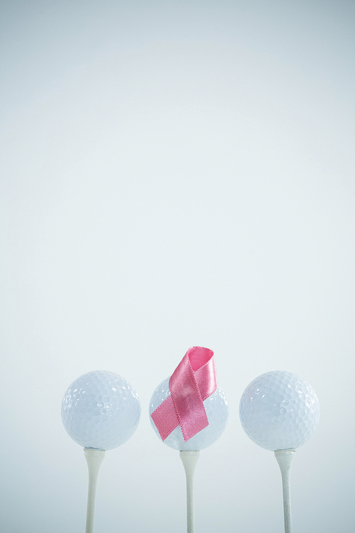 Pink Breast Cancer ribbon on golf ball against white background