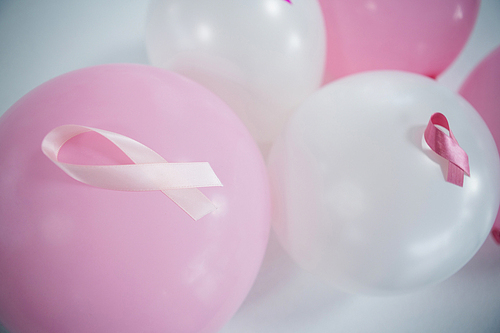 High angle view of pink Breast Cancer Awareness ribbons on balloons against white background
