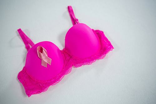 High angle view of Breast Cancer Awareness ribbon on pink bra against white background