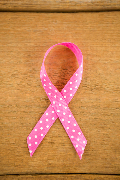 Directly above view of spotted pink Breast Cancer Awareness ribbon on wooden table
