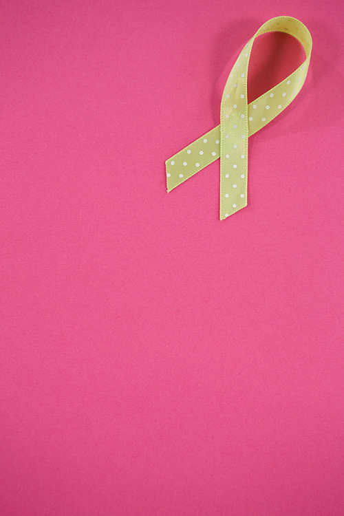 High angle view of spotted green Lymphoma Awareness ribbon on pink background