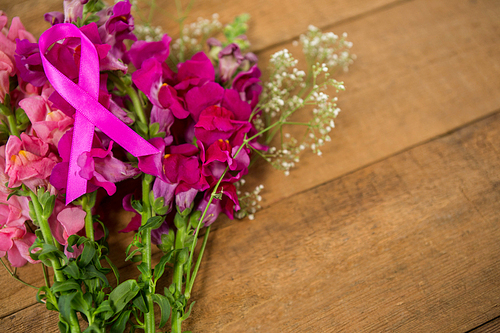 High angle view of pink Breast Cancer Awareness ribbon on flowers over wooden table