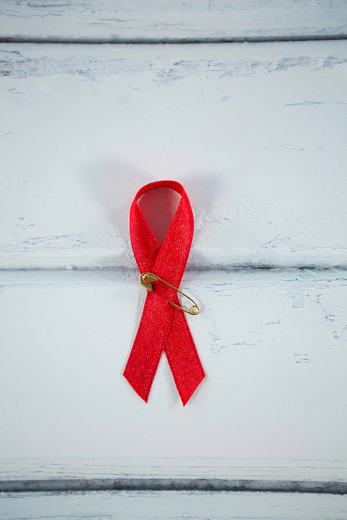 Overhead view of red AIDS awareness ribbon on white wooden table