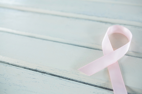 Close-up of pink Breast Cancer Awareness ribbon on white wooden table