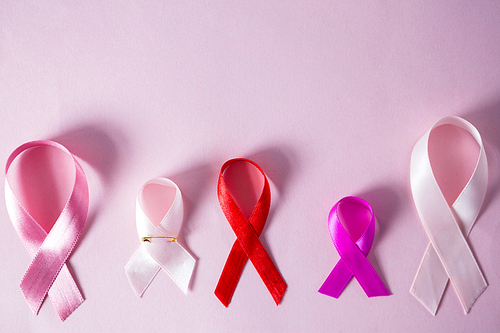 Close-up of various awareness ribbons on pink background