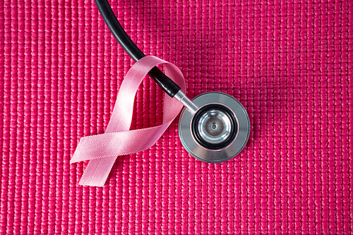 Directly above view of stethoscope by pink Breast Cancer Awareness ribbon on fabric