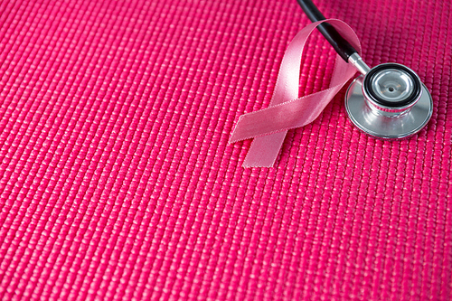 High angle view of stethoscope by pink Breast Cancer Awareness ribbon on fabric