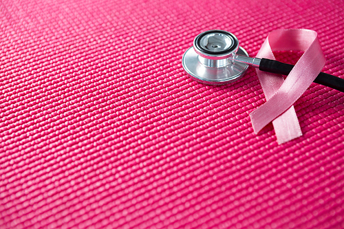 High angle view of pink Breast Cancer Awareness ribbon with stethoscope on fabric