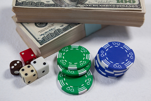 Close-up of US dollars, dice and casino chips on white background