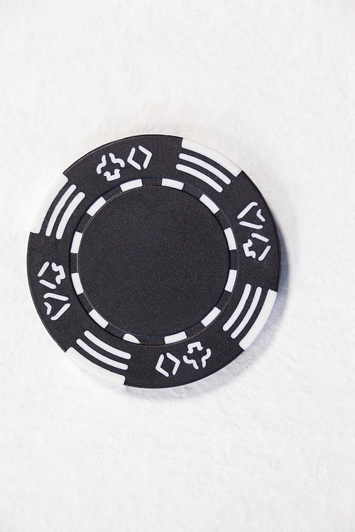 Close-up of black casino chip on white background