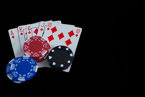 High angle view of cards and chips on black background