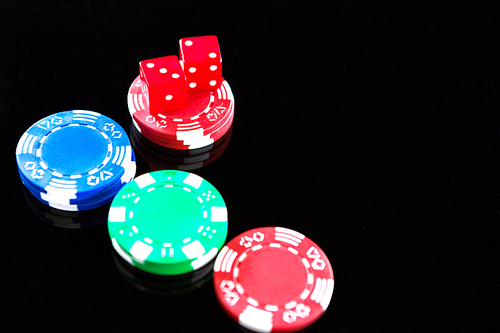 High angle view of red dices with chips on black background