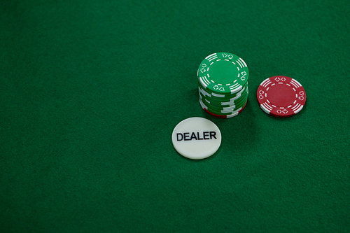 High angle view of dealer coin with chips on green table